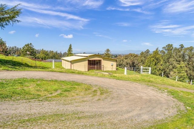 view of front of home with an exterior structure, curved driveway, an outdoor structure, a rural view, and a pole building