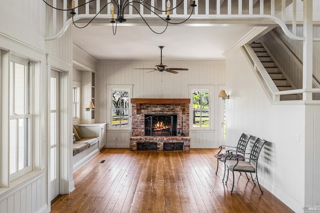 living room with hardwood / wood-style floors, ceiling fan with notable chandelier, and a fireplace