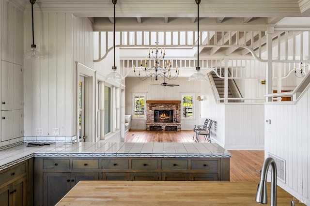 kitchen with a fireplace, beam ceiling, hardwood / wood-style floors, and tile counters