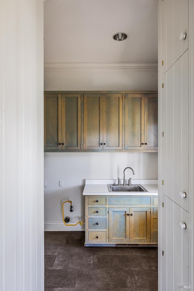 kitchen with dark tile floors, ornamental molding, and sink