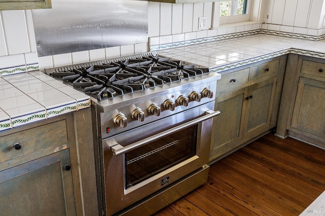 kitchen with backsplash, designer range, dark hardwood / wood-style floors, and tile counters