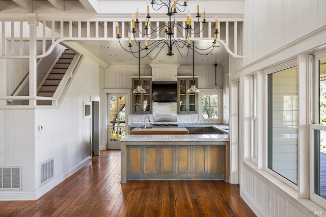 kitchen with pendant lighting, a notable chandelier, a towering ceiling, fridge, and dark hardwood / wood-style flooring