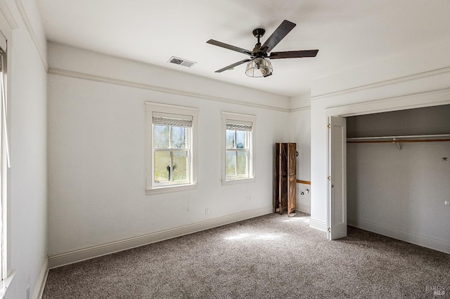 unfurnished bedroom featuring ceiling fan, dark colored carpet, and a closet