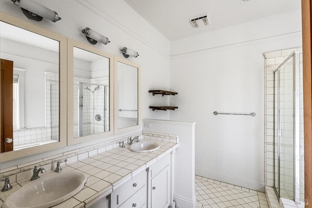 bathroom with tile floors, dual vanity, and a shower with door