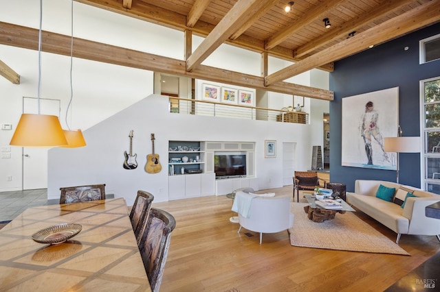 living area featuring beamed ceiling, a high ceiling, wooden ceiling, and wood finished floors