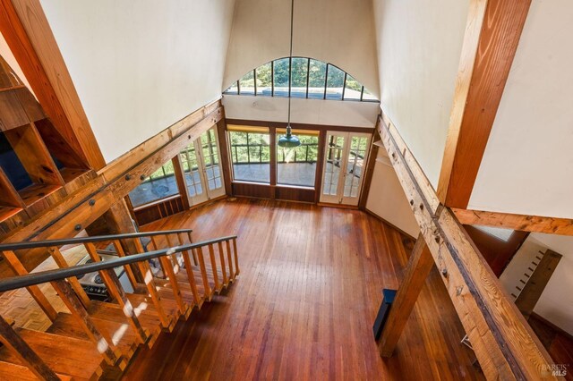 stairway featuring wood-type flooring, a high ceiling, and french doors