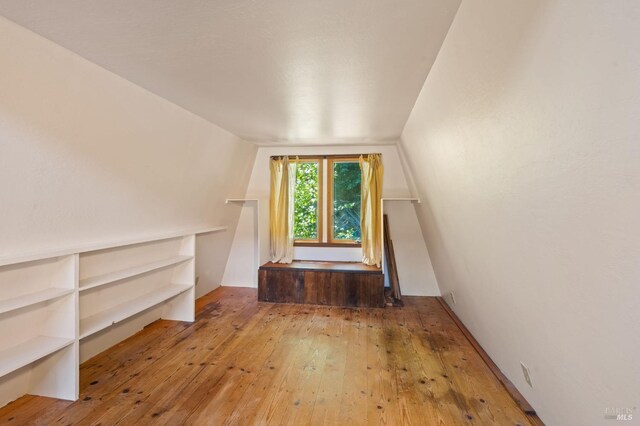 additional living space featuring hardwood / wood-style floors and vaulted ceiling