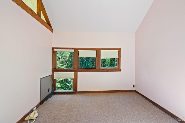 carpeted spare room with high vaulted ceiling