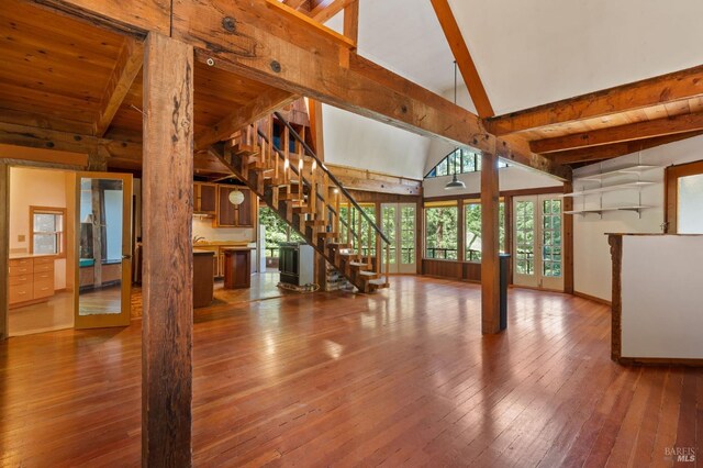 unfurnished living room with hardwood / wood-style flooring, beam ceiling, and high vaulted ceiling