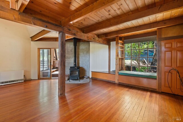 unfurnished living room featuring beam ceiling, a wood stove, radiator, wooden ceiling, and wood-type flooring