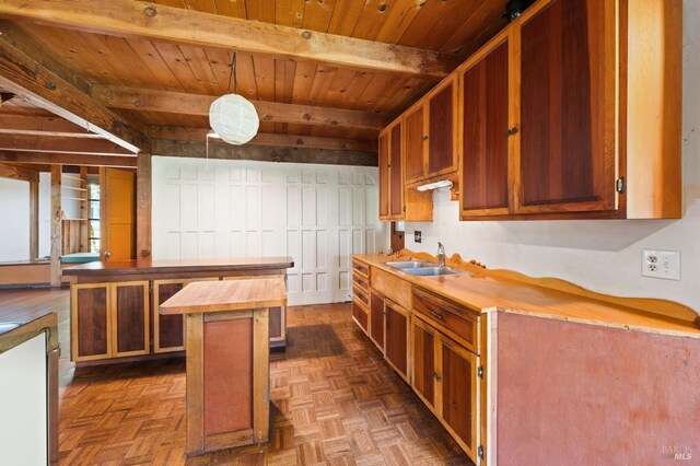 kitchen with dark parquet floors, sink, a kitchen island, hanging light fixtures, and butcher block counters