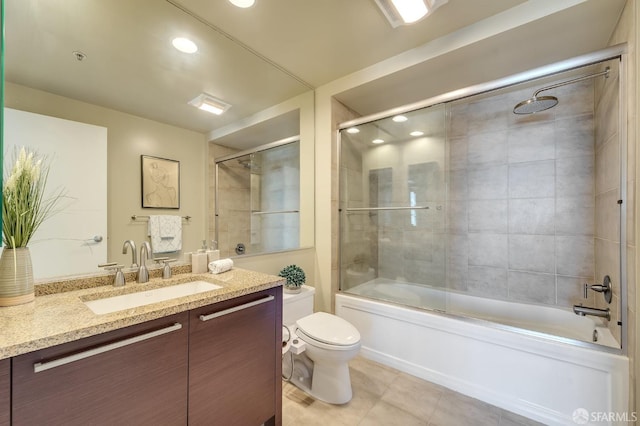 full bathroom with bath / shower combo with glass door, vanity, tile patterned floors, and toilet