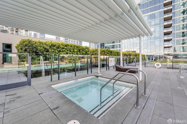 view of swimming pool featuring a hot tub and a patio