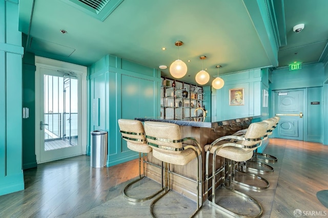 bar with dark wood-type flooring and hanging light fixtures