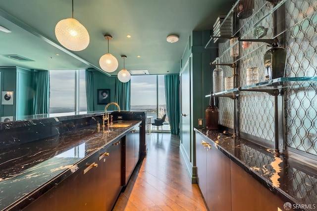 kitchen with pendant lighting, dark stone counters, floor to ceiling windows, and light wood-type flooring