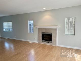 unfurnished living room with wood-type flooring and a tile fireplace