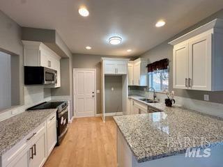 kitchen featuring white cabinets, stainless steel appliances, sink, and light wood-type flooring