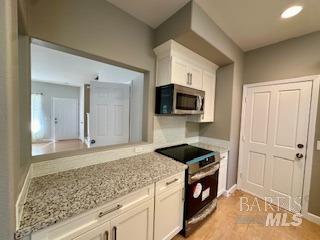 kitchen with appliances with stainless steel finishes, white cabinets, and light stone counters