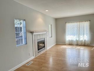 unfurnished living room with a fireplace and light hardwood / wood-style floors