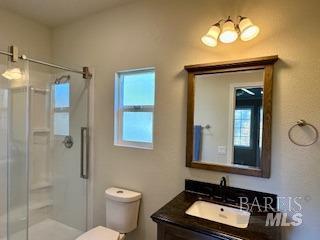 bathroom featuring walk in shower, vanity, and toilet