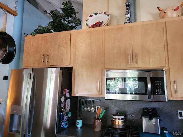 kitchen with stainless steel appliances, light brown cabinetry, and backsplash