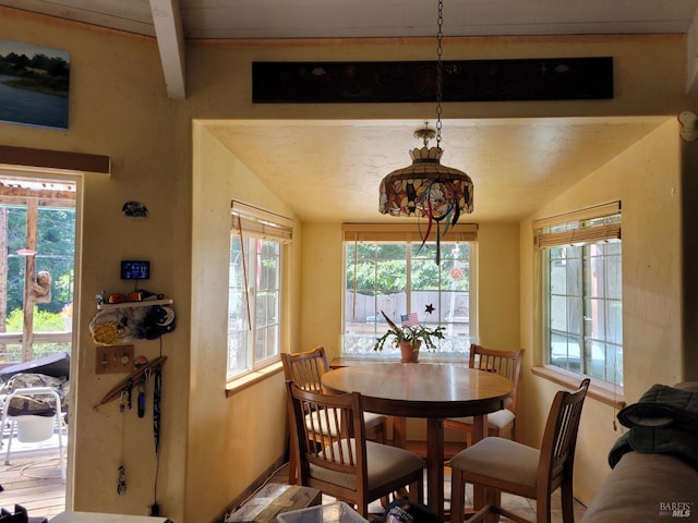 dining area with a wealth of natural light and lofted ceiling with beams