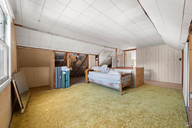 unfurnished bedroom featuring carpet flooring, wooden walls, and vaulted ceiling