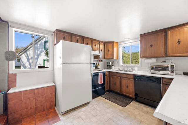 kitchen with stove, exhaust hood, white refrigerator, sink, and black dishwasher