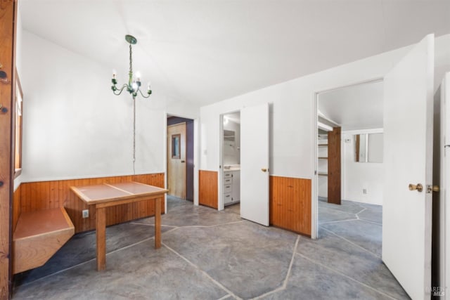 dining area with wood walls, concrete floors, and a chandelier