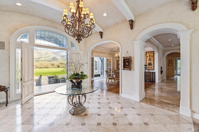 foyer with beamed ceiling, a mountain view, a notable chandelier, tile floors, and ornate columns