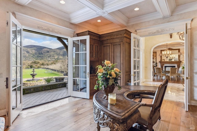 dining space featuring ornamental molding, light hardwood / wood-style floors, a mountain view, and coffered ceiling