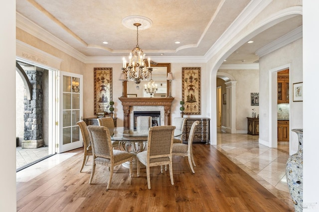 dining area featuring wood-type flooring, a tray ceiling, a chandelier, and crown molding