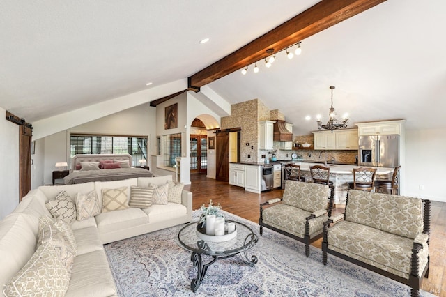 living room featuring dark hardwood / wood-style flooring, a barn door, beam ceiling, sink, and a notable chandelier