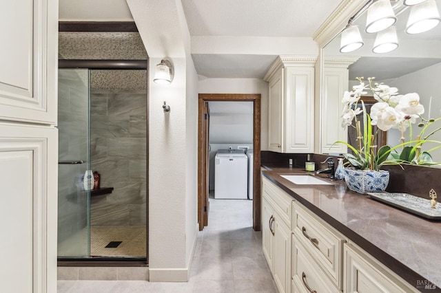 bathroom featuring walk in shower, oversized vanity, washer / dryer, and tile floors