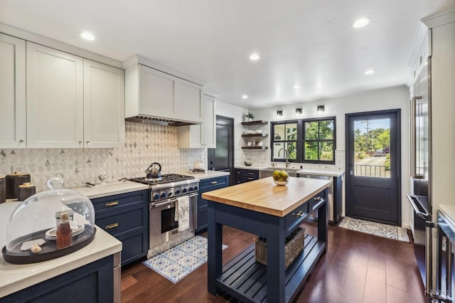 kitchen with dark wood-type flooring, blue cabinets, butcher block countertops, high end stainless steel range oven, and white cabinets