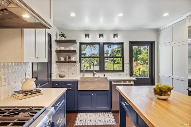 kitchen with backsplash, stainless steel dishwasher, sink, butcher block countertops, and white cabinetry