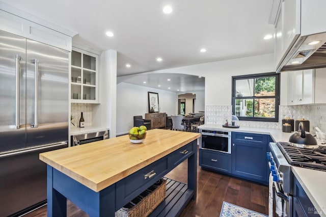 kitchen with blue cabinetry, white cabinetry, dark wood-type flooring, premium appliances, and wooden counters