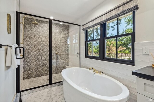 bathroom with vanity, plus walk in shower, and tile walls