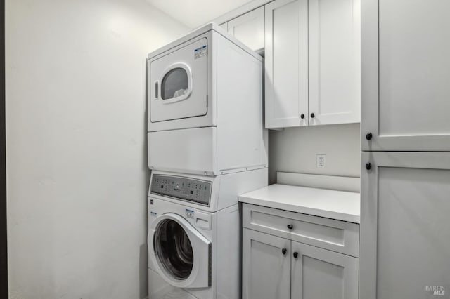 laundry room with stacked washer and dryer and cabinets