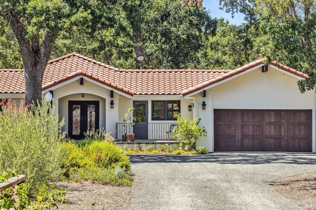 mediterranean / spanish-style house with covered porch and a garage