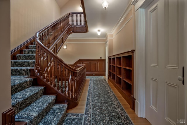 stairway featuring light hardwood / wood-style floors, crown molding, and a towering ceiling