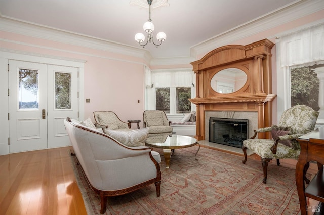 sitting room featuring a wealth of natural light, light hardwood / wood-style floors, an inviting chandelier, and crown molding