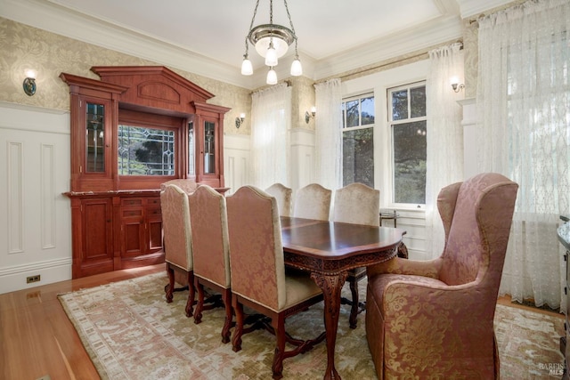 dining area with light hardwood / wood-style flooring, crown molding, and an inviting chandelier