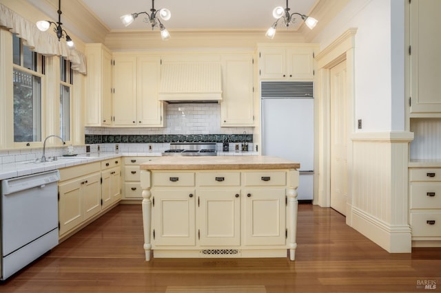 kitchen with pendant lighting, custom exhaust hood, dishwasher, and sink