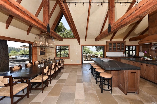 interior space featuring a healthy amount of sunlight, high vaulted ceiling, beamed ceiling, and light tile floors