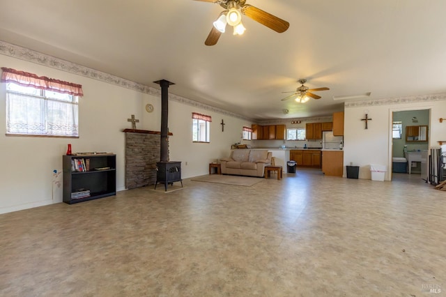 living room with plenty of natural light, ceiling fan, and a wood stove