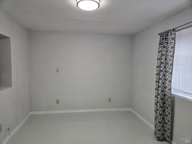 unfurnished room with baseboards