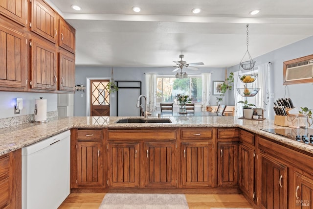 kitchen featuring brown cabinetry, a peninsula, a sink, dishwasher, and black electric stovetop