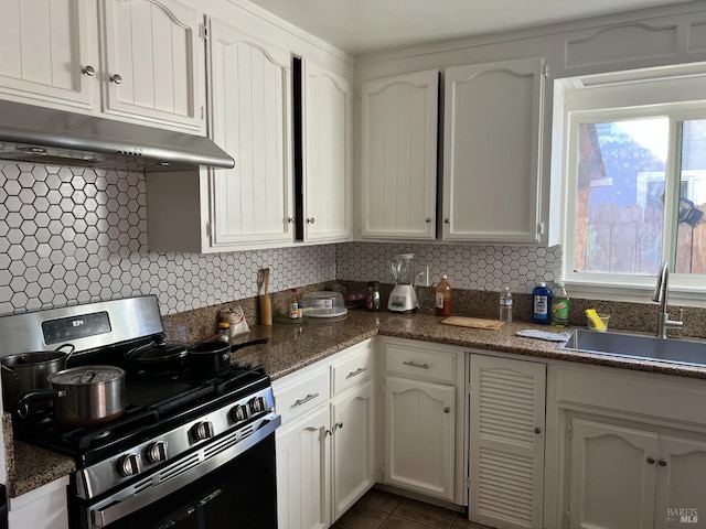 kitchen with stainless steel gas range, sink, white cabinetry, dark tile patterned flooring, and decorative backsplash