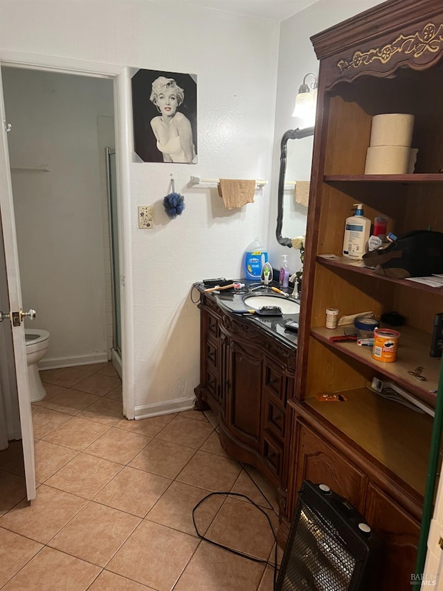 bathroom with tile patterned flooring, vanity, a shower with door, and toilet